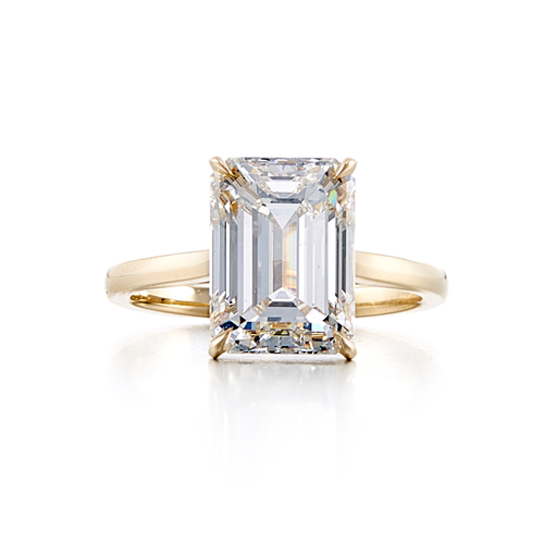 A solitaire style engagement ring with a 18 karat yellow gold band and a 5 carat emerald cut center stone that is a G color and SI1 clarity according to GIA.