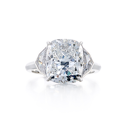 A three-stone style engagement ring with a platinum band and a cushion cut diamond.